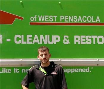 Male employee with short dark hair standing in front of a SERVPRO truck.