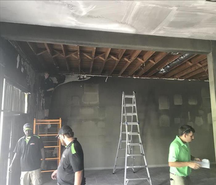 Crew at work completing the cleanup of the charred and burnt studio, exposed ceiling after removal of sheetrock, stained wall